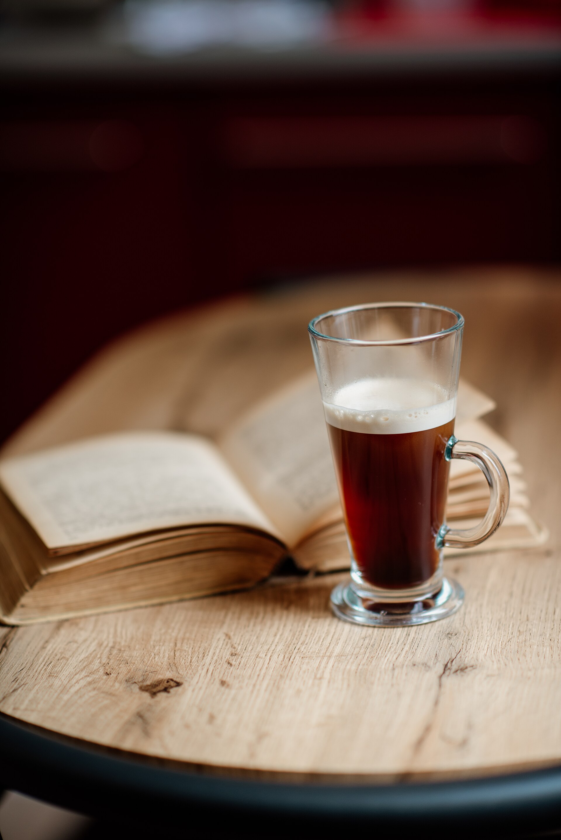 An open book and a white coffee cup on a wooden table. Illustrative photograph, not a booked table.